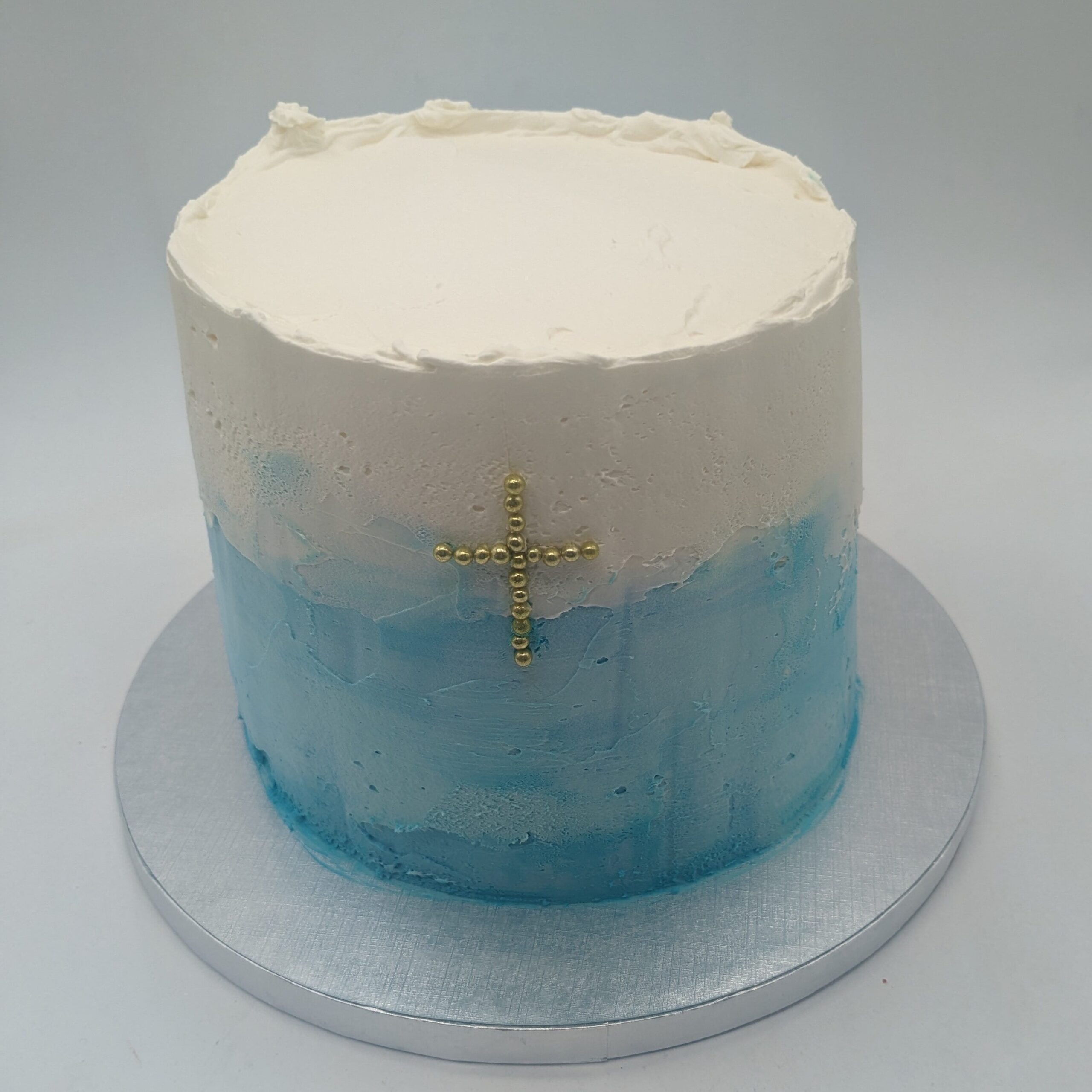 Cake design baptême blanc et bleu avec une croix